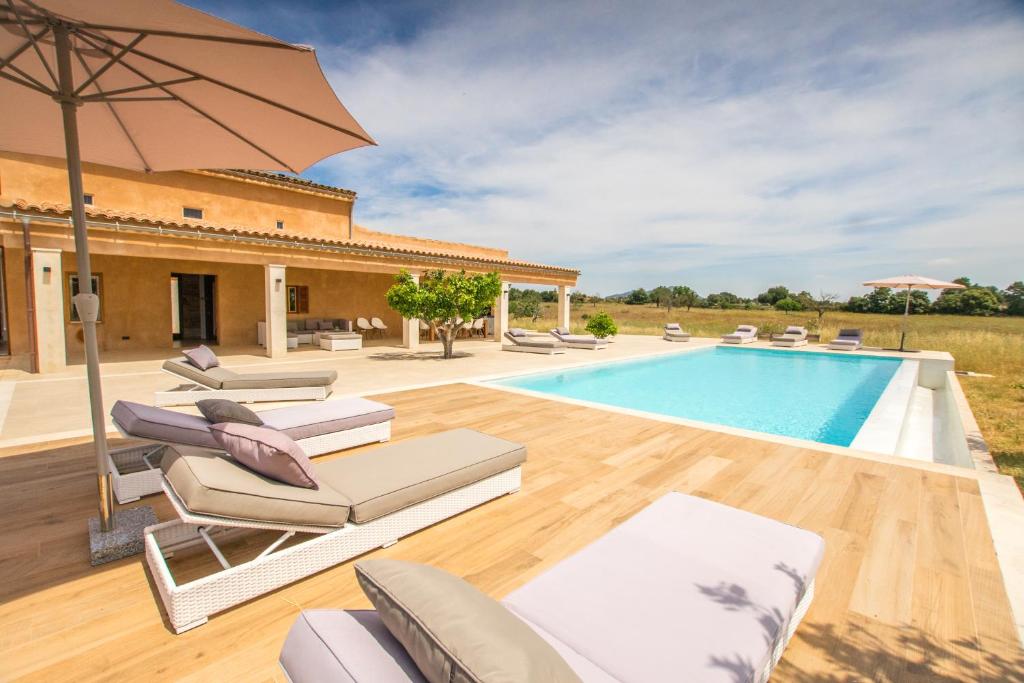 een villa met een zwembad met stoelen en een parasol bij Can Toño in Inca