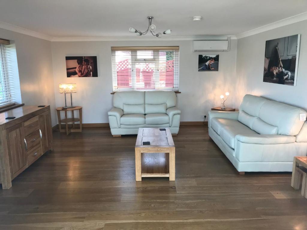 ein Wohnzimmer mit einem Sofa und einem Tisch in der Unterkunft The Bungalow in Billericay