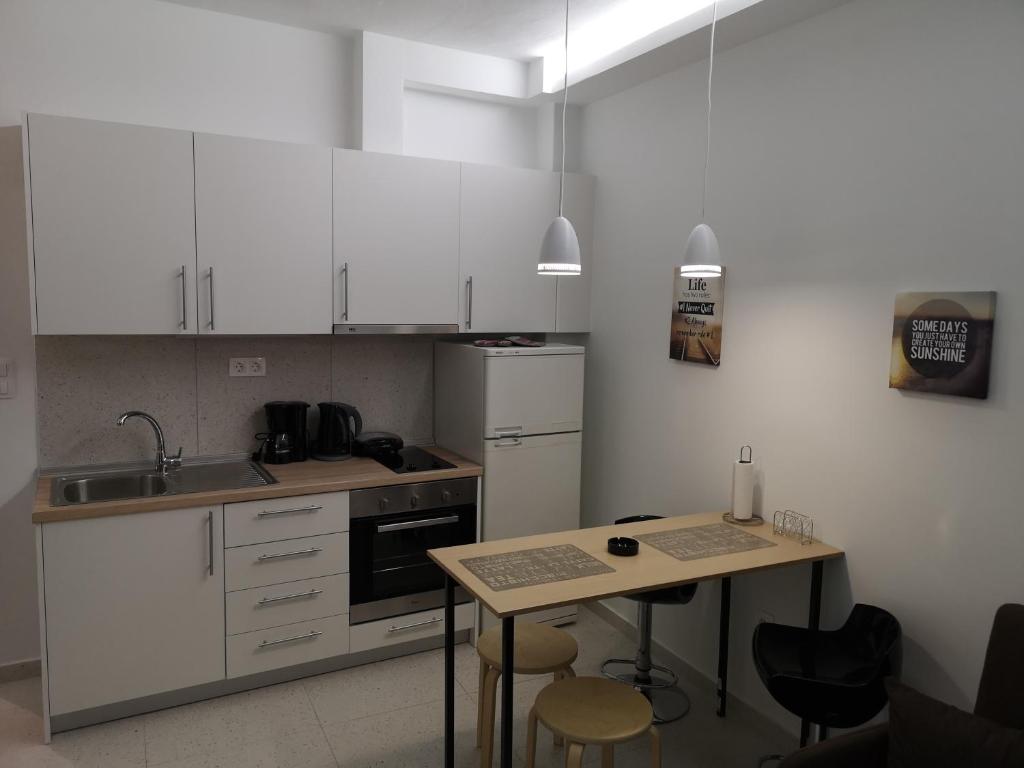 una cocina con armarios blancos y una mesa con sillas. en Dimitris House 7 en Tesalónica