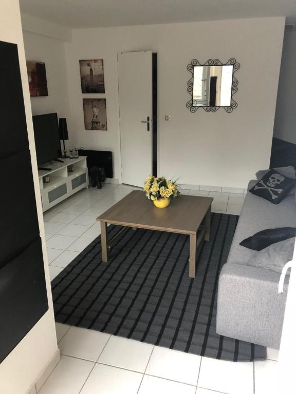 uma sala de estar com uma mesa e um sofá em JOLIE PETITE MAISON em Villepinte