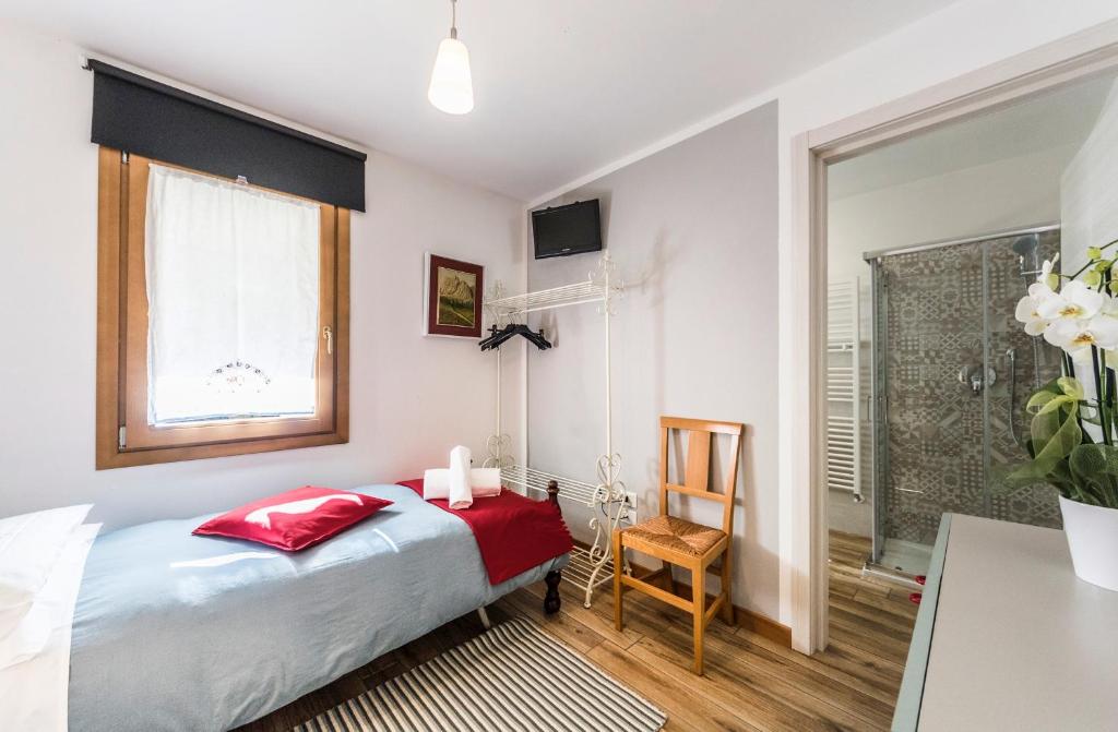 a bedroom with a bed and a window and a chair at LA LOGGETTA affittacamere in Bassano del Grappa