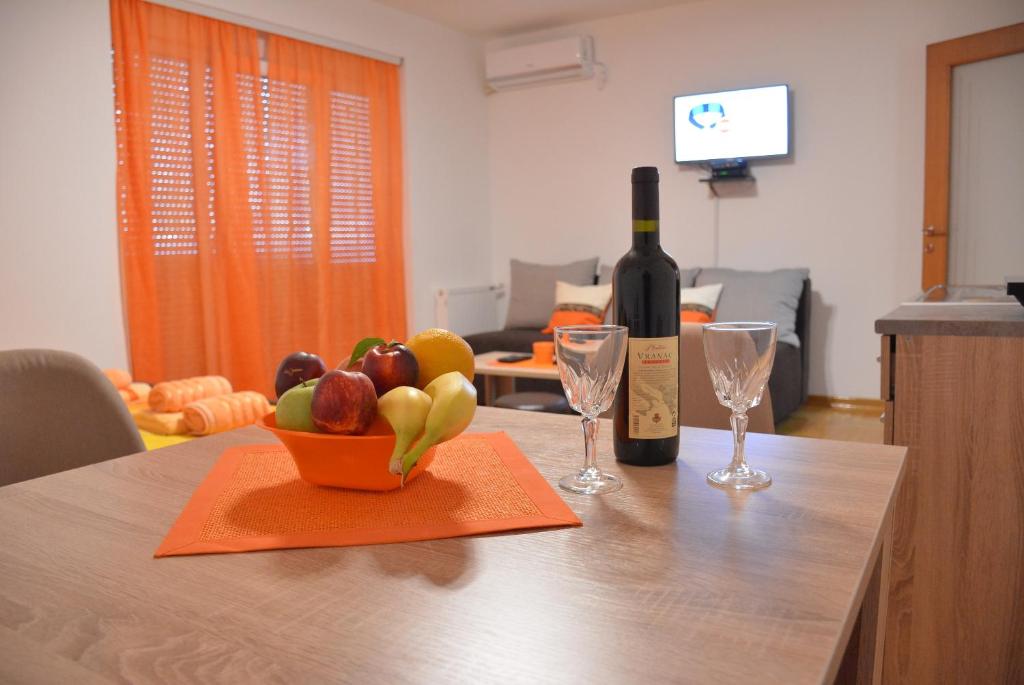 Apartman Radmanovac في Vrnjačka Banja: زجاجة من النبيذ ووعاء من الفواكه على طاولة