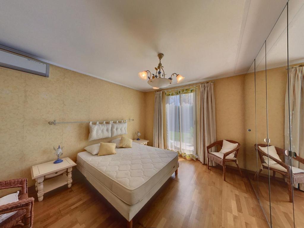 - une chambre avec un grand lit blanc et une chaise dans l'établissement Villa Bruyere, à Antibes