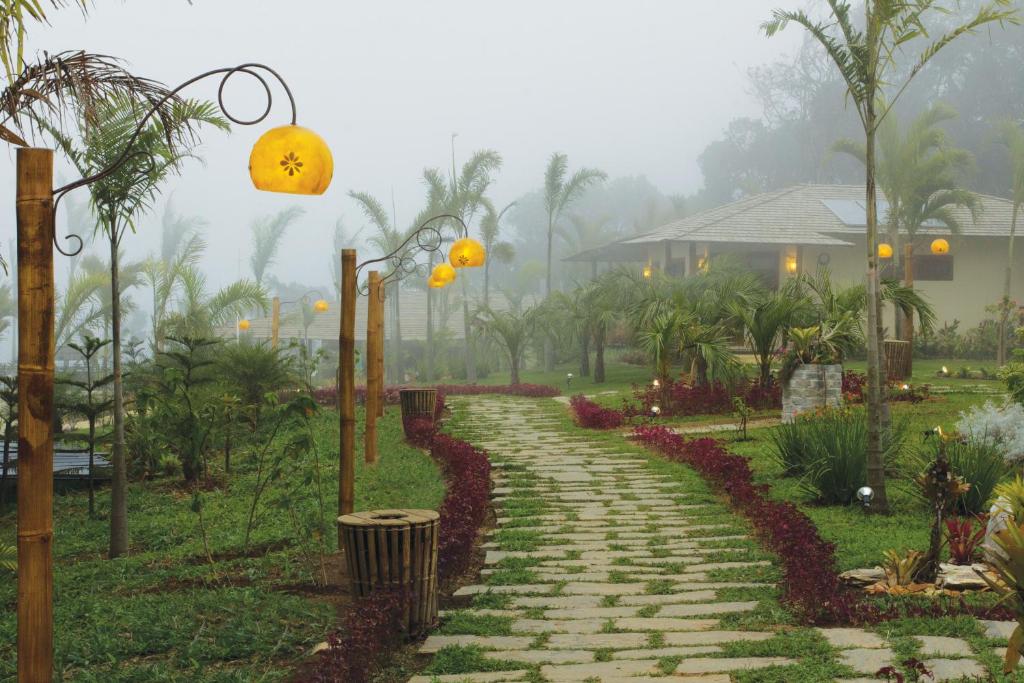 a stone path in a garden with lamps and a house at Hotel Vale das Nuvens in Guaramiranga