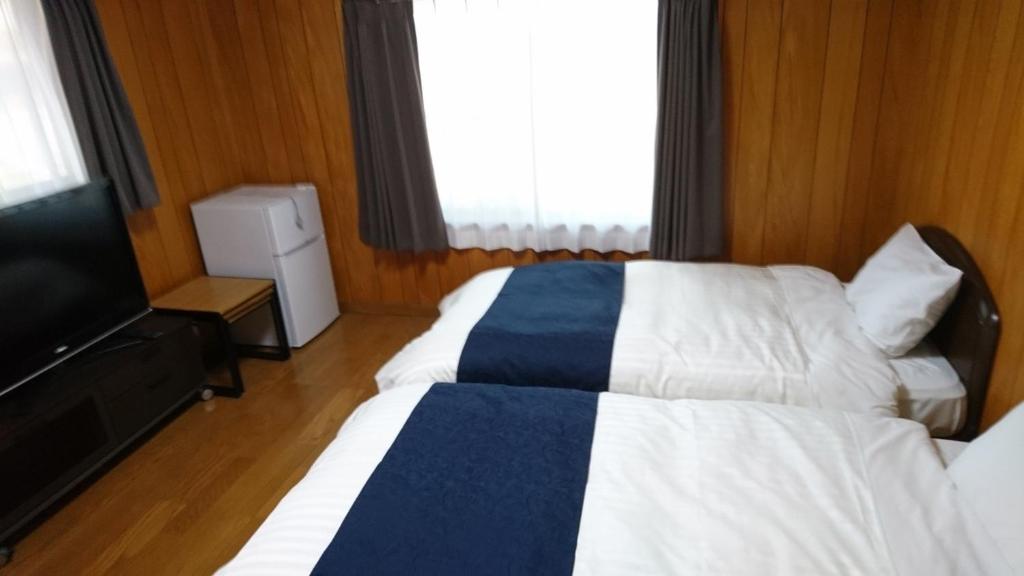 a hotel room with two beds and a flat screen tv at Minpaku Nagashima room5 / Vacation STAY 1034 in Kuwana