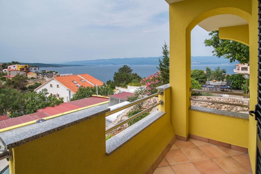 a yellow balcony with a view of the water at Apartment Vrbnik 2 in Vrbnik