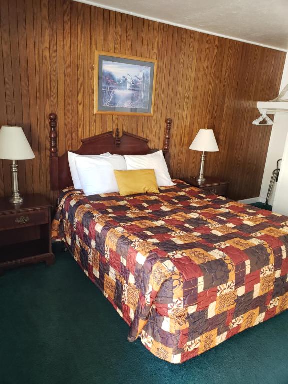 a bedroom with a bed with a colorful quilt and two lamps at Mother Lode Lodge in Mariposa
