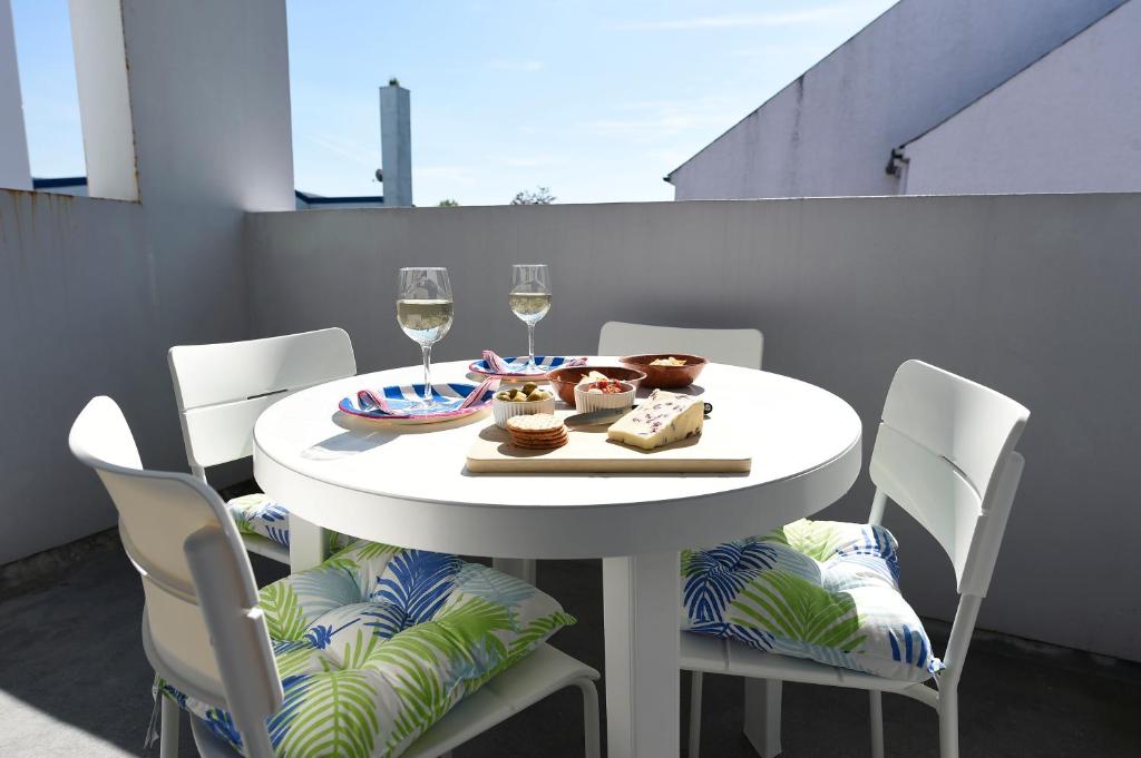 una mesa blanca y sillas con copas de vino en Causeway Coast Apartments Kyla Marine, en Ballycastle