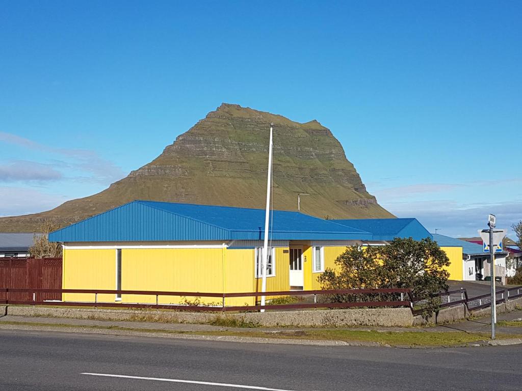 a yellow building with a mountain in the background at Sæból/Ocean Lair in Grundarfjordur