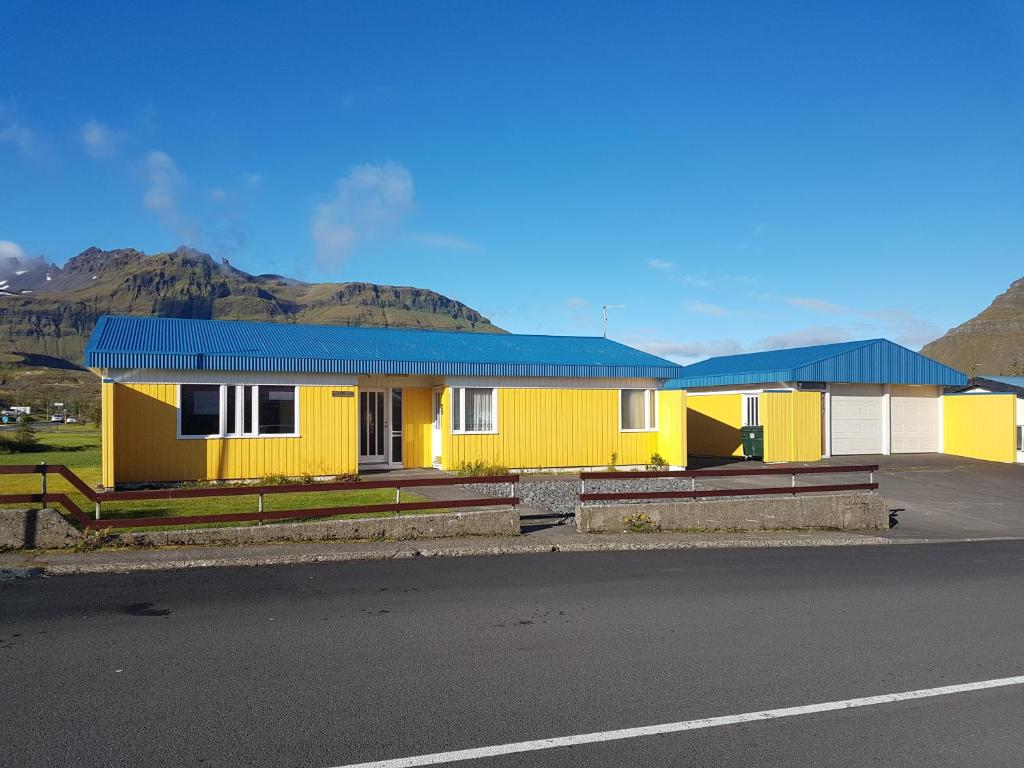 une maison jaune avec un toit bleu sur le côté de la route dans l'établissement Sæból/Ocean Lair 2, à Grundarfjörður