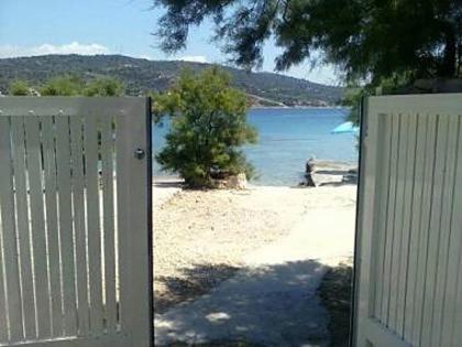 a white gate on a beach with a body of water at Holiday home Ivica - by the sea in Sevid