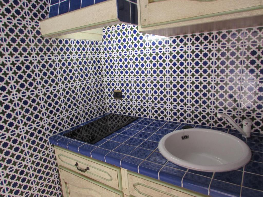 a bathroom with a sink and a blue tiled wall at Résidence Royal Palmeraie in Aubagne