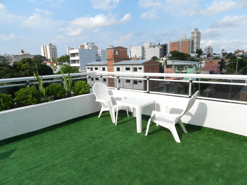 a balcony with two white chairs and green grass at El Departamento de los Abuelos in Posadas