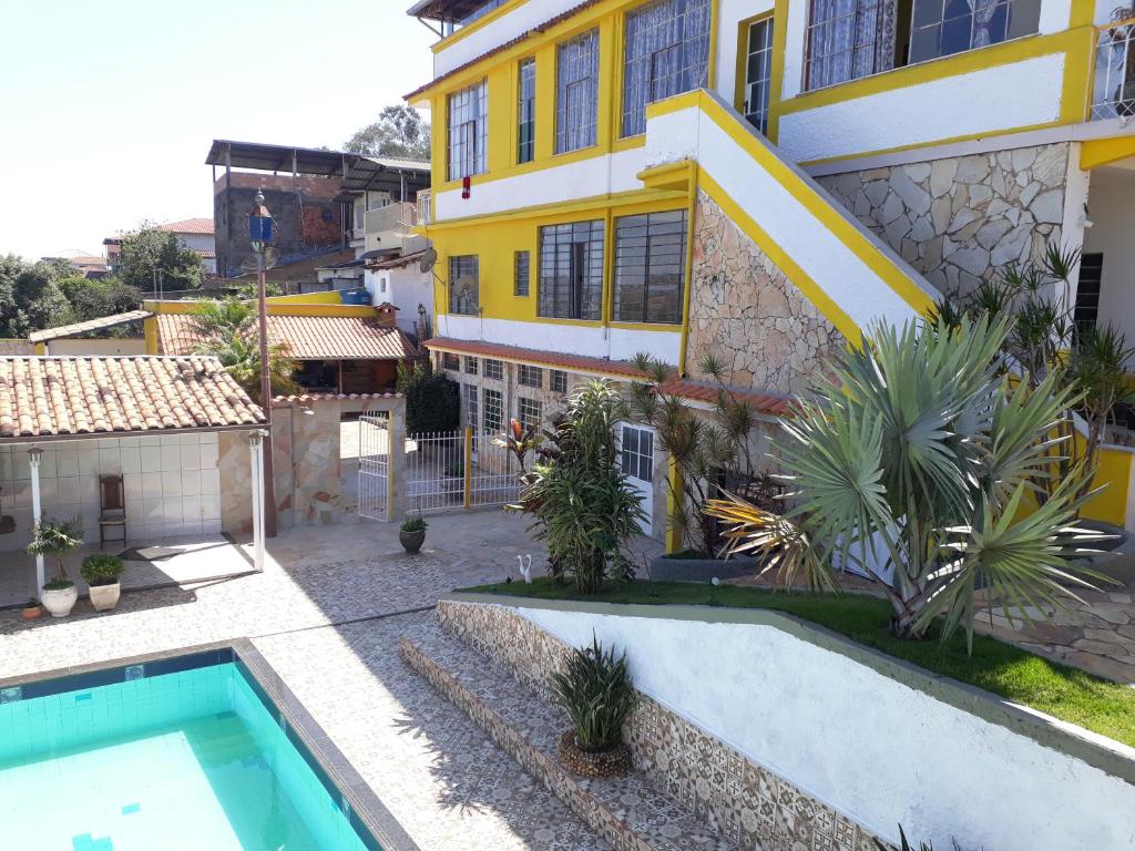 a house with a swimming pool in front of it at Pousada Raio De Sol in São João del Rei