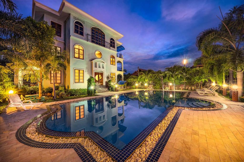 ein Haus mit einem Pool vor einem Gebäude in der Unterkunft Baan Georges Hotel in Sukhothai