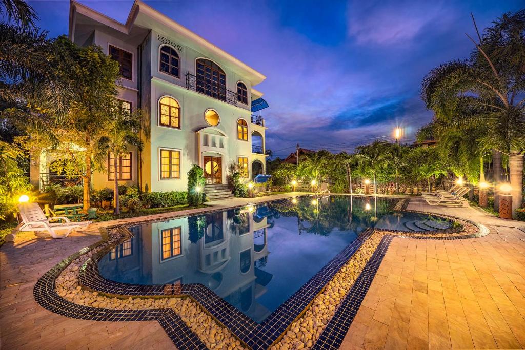 a house with a swimming pool in front of a building at Baan Georges Hotel in Sukhothai