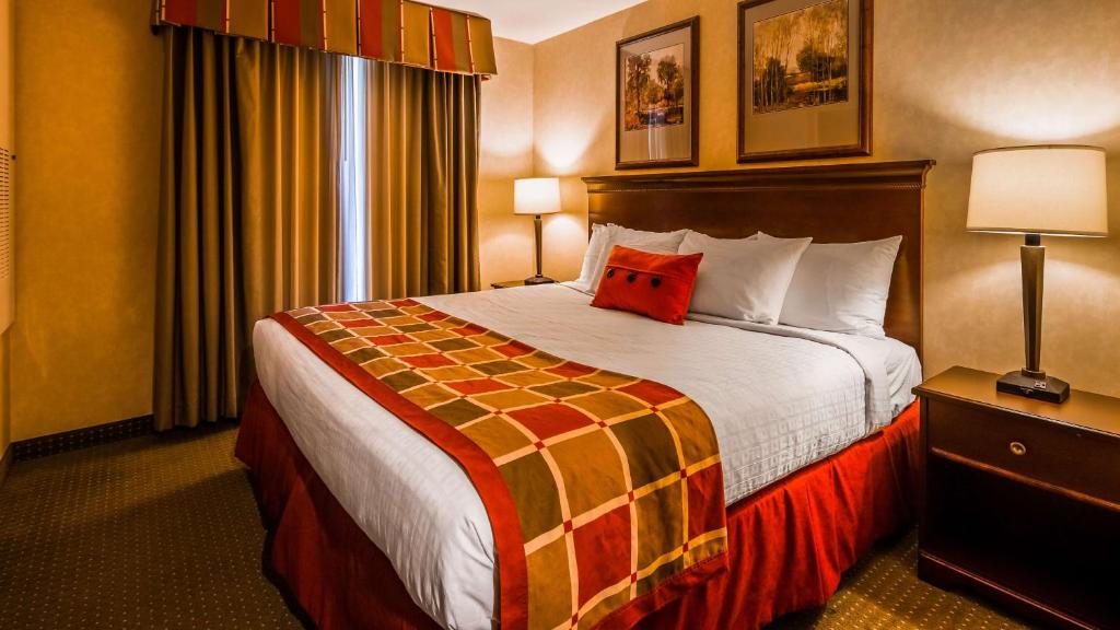 a hotel room with a bed with a red pillow on it at Best Western Plus Ticonderoga in Ticonderoga