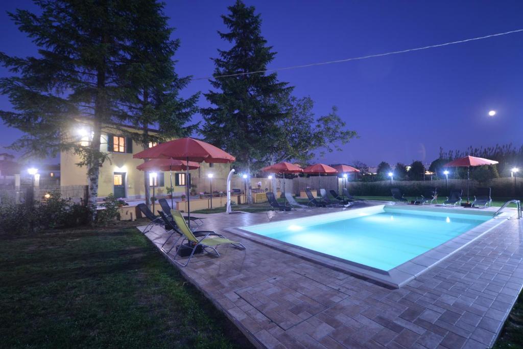 uma piscina com cadeiras e guarda-sóis à noite em tenuta braccini em Montecatini Terme
