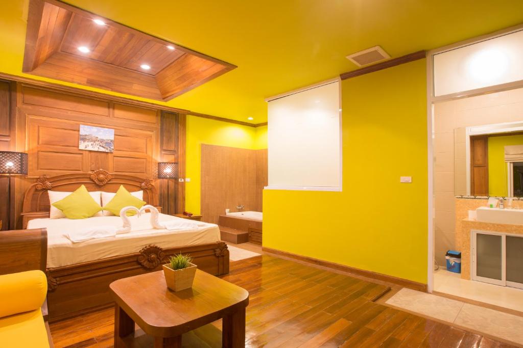 A spacious yellow-and-wood bedroom with a carved bed and visible bathroom entrance.