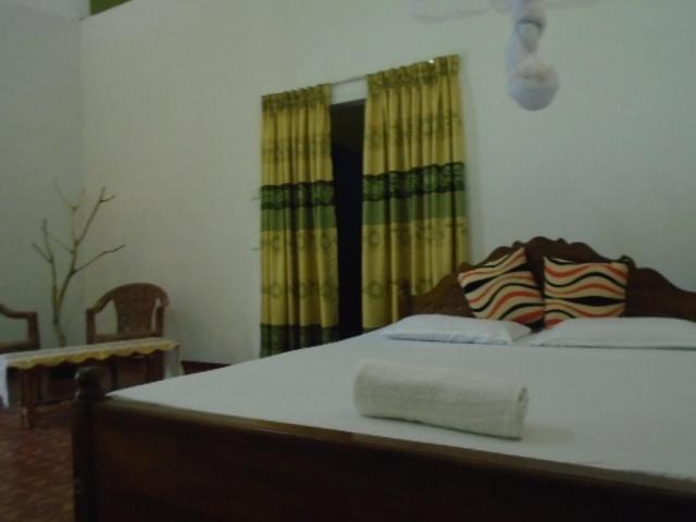 a bedroom with a bed with a towel on it at Jungle House Tourist Inn in Dambulla