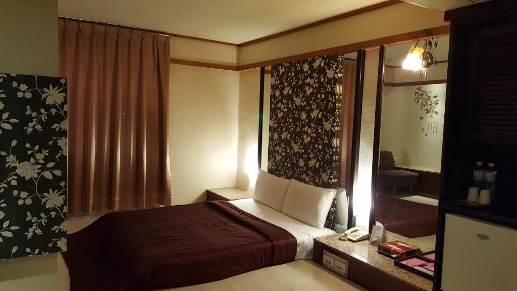 a hotel room with a bed and a window at Windmill Fashion Hotel in Kaohsiung