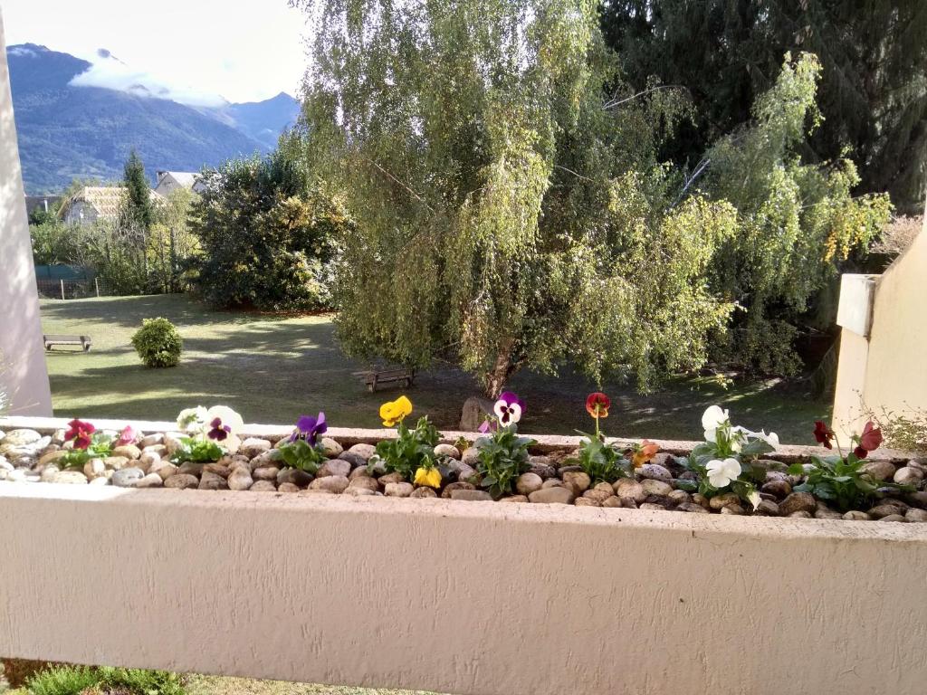 einen Blumengarten an einer Wand mit Blumen in der Unterkunft Les Berges Du Gave D'azun in Argelès-Gazost