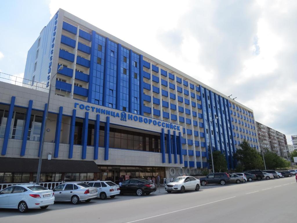 un gran edificio con coches estacionados en un estacionamiento en Hotel Novorossiysk, en Novorossiysk