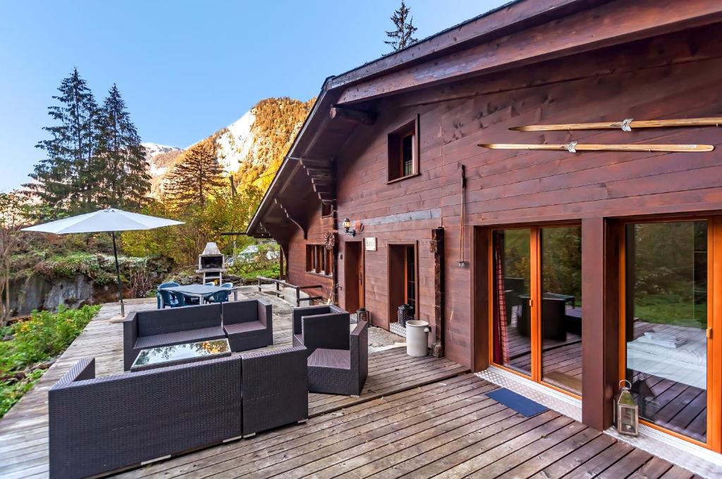een houten terras met stoelen en een parasol bij Charming Little Chalet for 6 People & Free Ski Lockers in Grindelwald