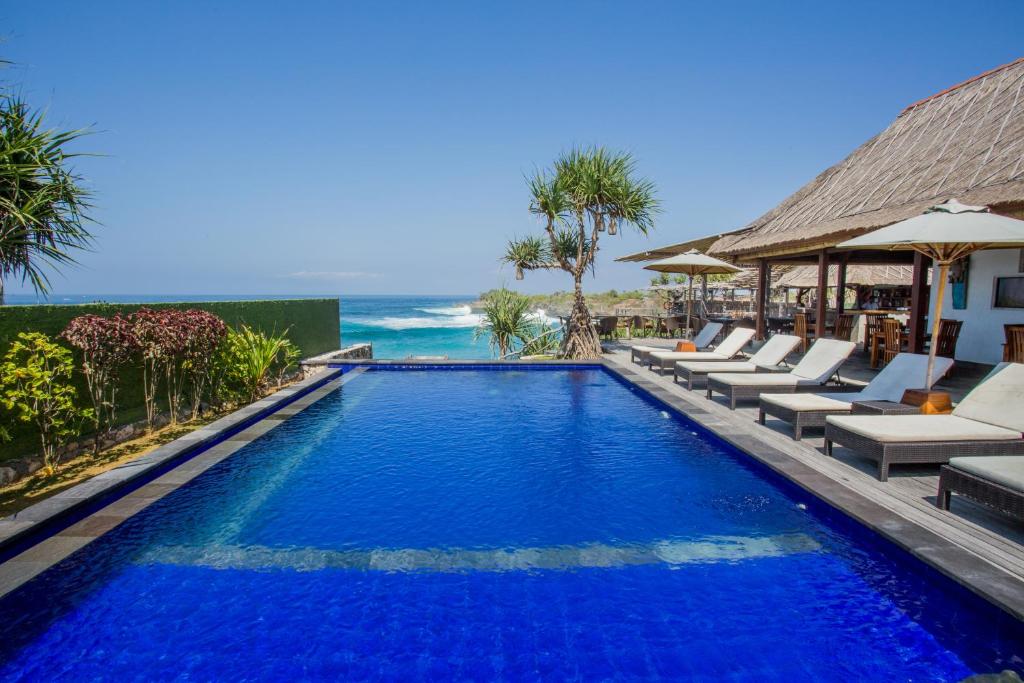 a swimming pool with lounge chairs and the ocean at Water Blow Huts in Nusa Lembongan