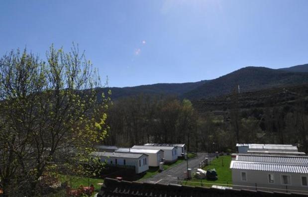 eine Gruppe von Gebäuden mit Bäumen und Bergen im Hintergrund in der Unterkunft Resort Camping Solopuent in Castiello de Jaca