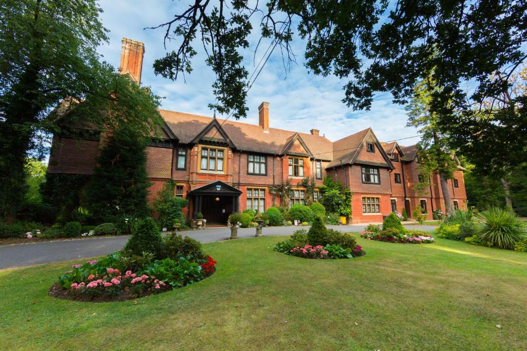 uma grande casa de tijolos com flores em frente em Stanhill Court Hotel em Charlwood