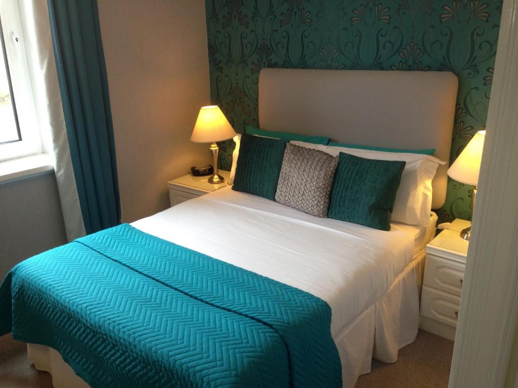 a bedroom with a bed with a blue and white comforter at Lairg Highland Hotel in Lairg