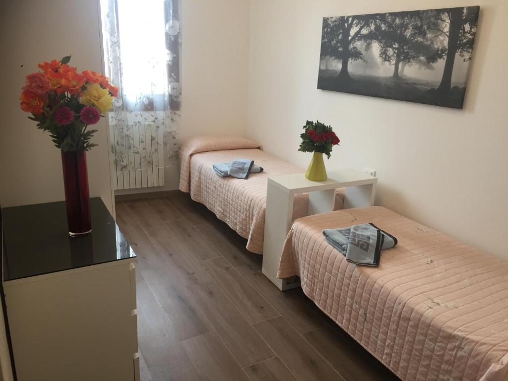 a room with two beds and a vase of flowers on a table at TINTORETTO 1 CON TERRAZZA SOPRA IL TETTO, 3 bagni, 3 grandi camere da letto, SUPER NUOVO in Venice