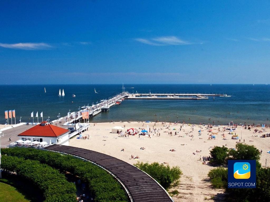 plaża z ludźmi na piasku i molo w obiekcie Sea Sail Apartments w mieście Sopot