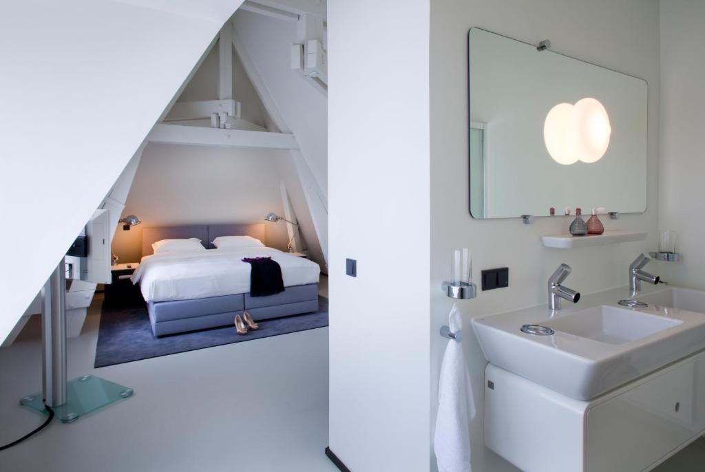 Urban Residences Maastricht في ماستريخت: غرفة نوم بسرير ومغسلة ومرآة