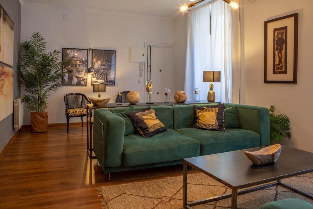 un soggiorno con divano verde e tavolo di Apartamento moderno junto a la Gran Via a Madrid