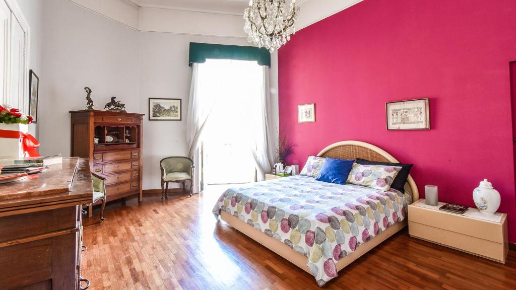 ナポリにあるLa stanza della Sirenaのピンクの壁のベッドルーム(ベッド1台、デスク付)