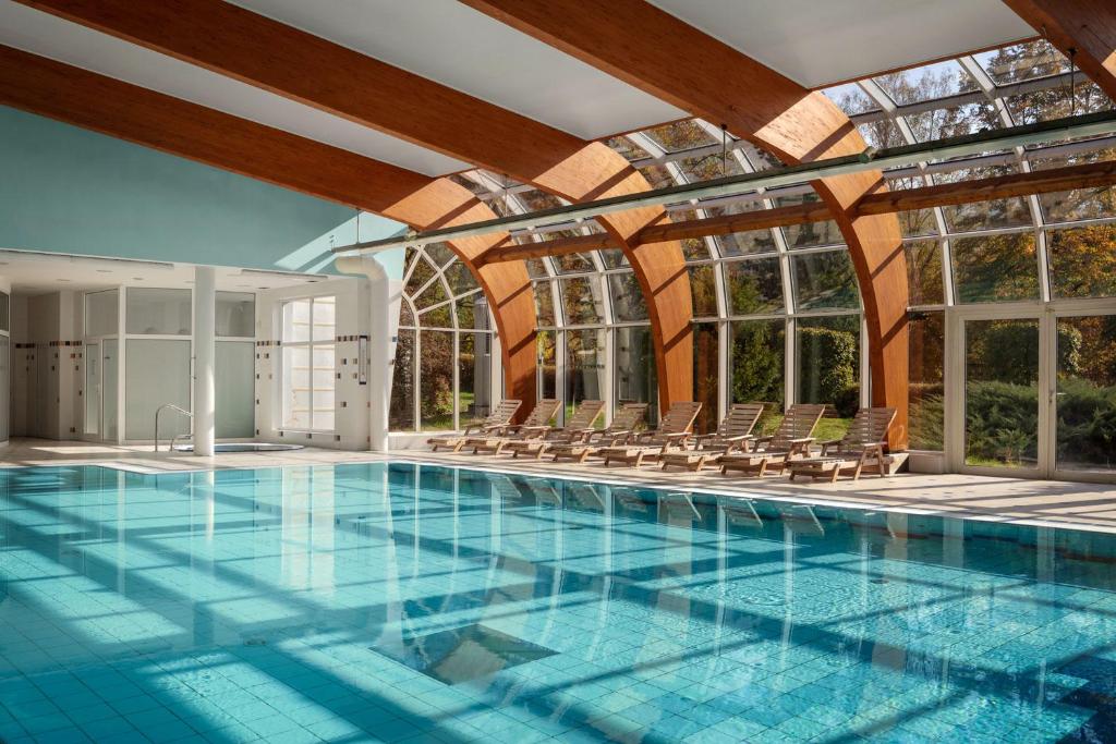 a large swimming pool with chairs and windows at Spa Resort Sanssouci in Karlovy Vary