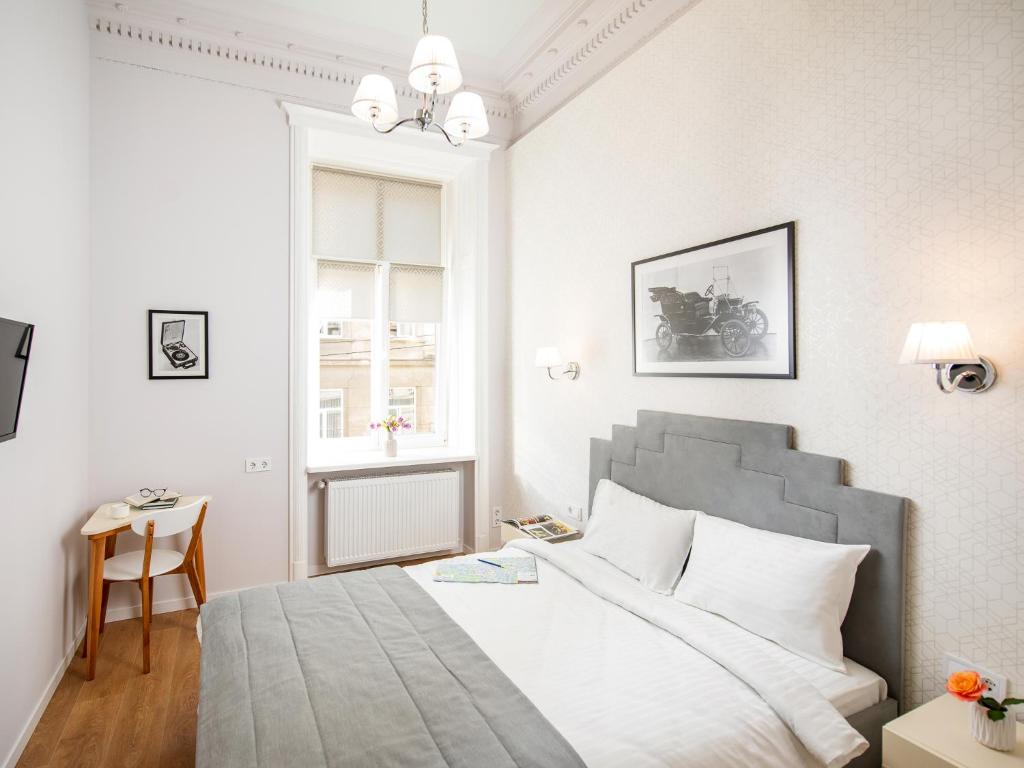- une chambre blanche avec un grand lit et une table dans l'établissement Art Deco Central Rooms, à Lviv