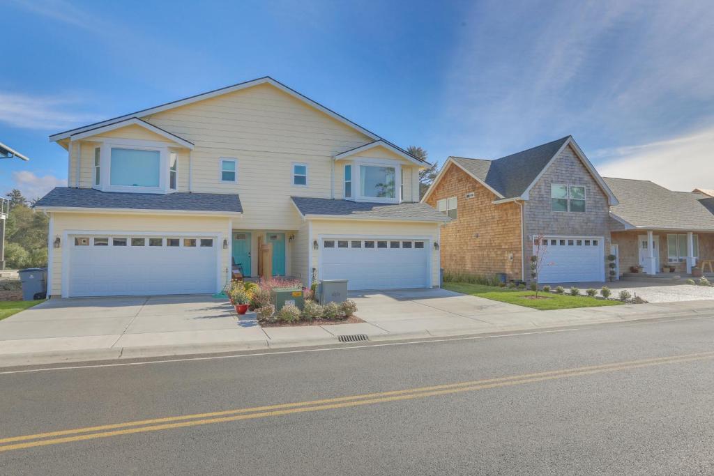 a house with white garage doors on a street at Lighthouse By The Cove in Seaside