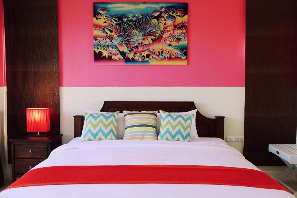 een slaapkamer met een groot bed met een roze muur bij OK Phuket in Kata Beach