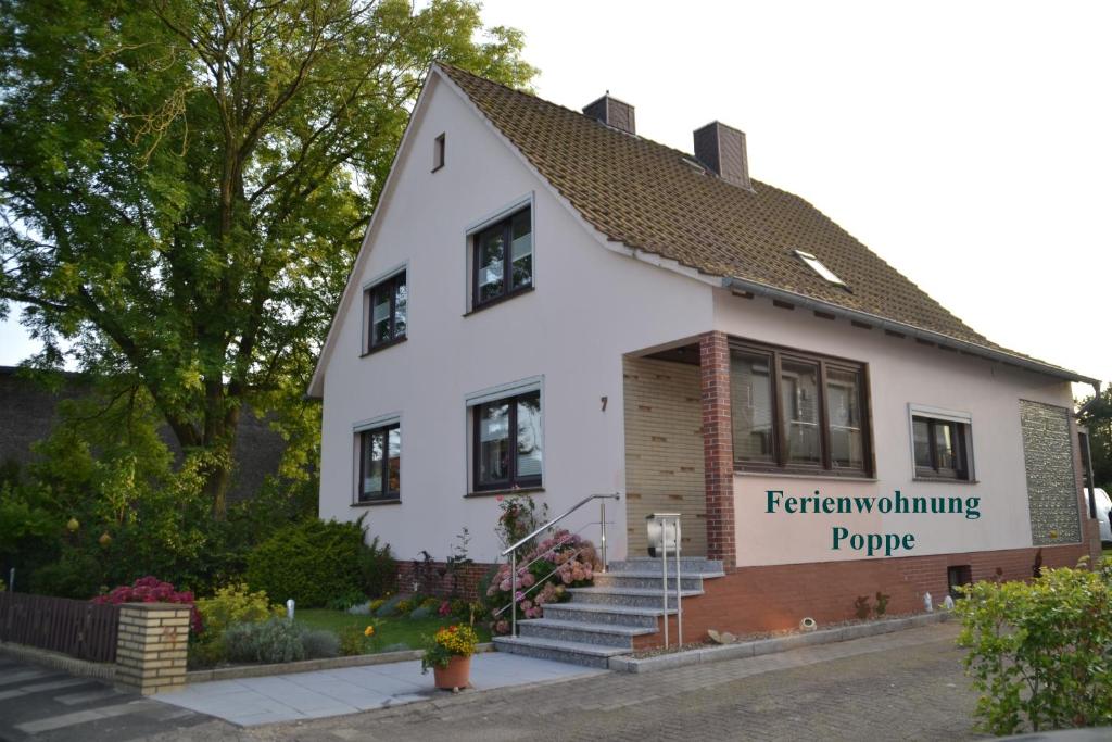 Ferienwohnung Poppe في Loxstedt: مبنى ابيض عليه لافته جانبيه