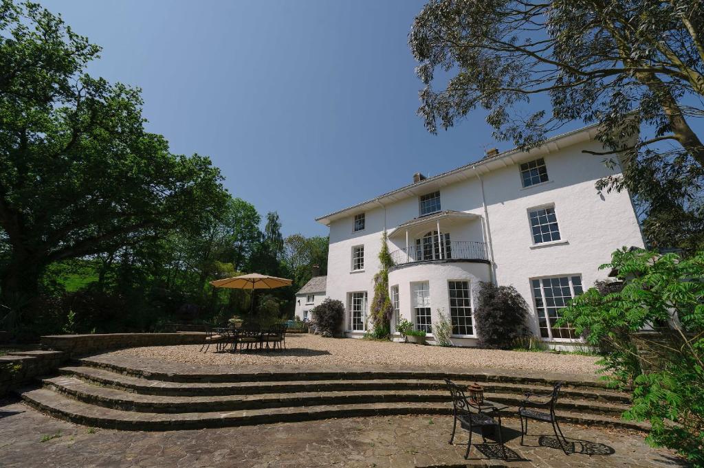 a large white building with benches and tables in front of it at Corffe House and Holiday Cottages in Barnstaple