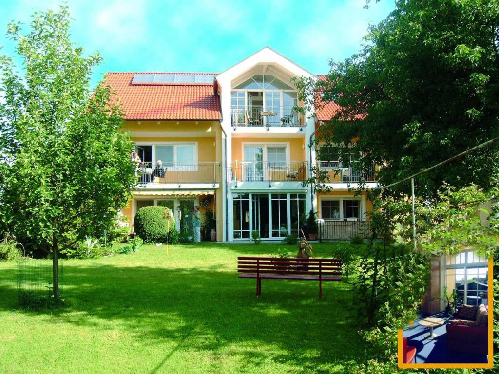 a large yellow house with a bench in the yard at Appartementhaus Löwenzahn in Bad Füssing