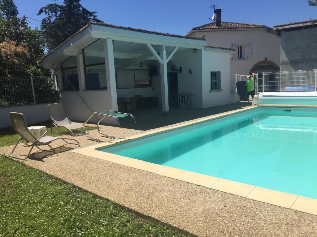 uma piscina com duas cadeiras ao lado de uma casa em Là Grange em Parisot