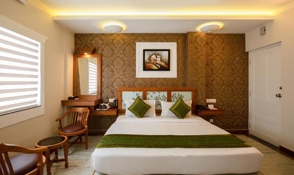 a hotel room with a bed and a table and chairs at Treebo The Qasr in Cochin