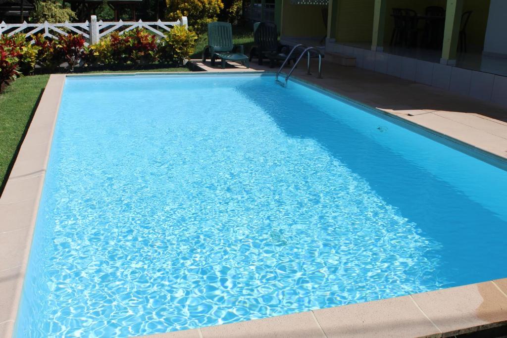 uma piscina com água azul num quintal em Villa Hausseman em Rivière-Pilote