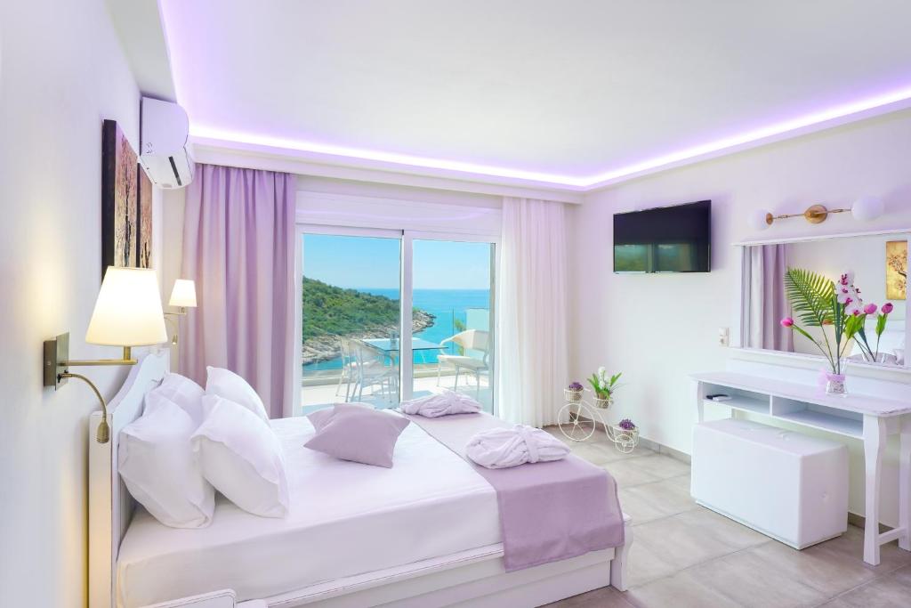 a white bedroom with a bed and a desk and a window at Dream View in Skala Marion