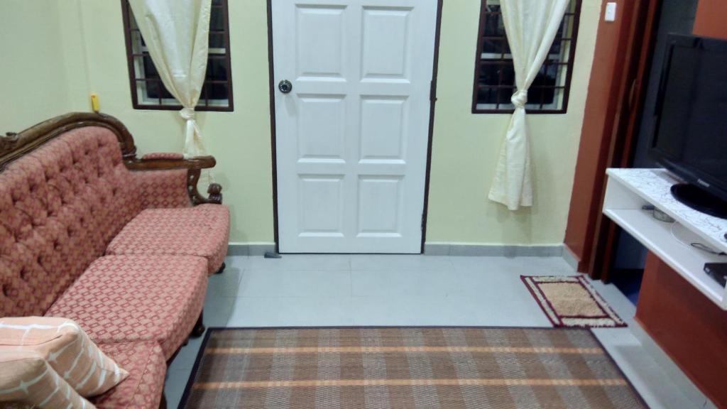 een kamer met een deur, een bank en een tv bij HOMESTAY KAMPUNG DELEK BARU, KLANG in Kampong Telok Gadong Kechil
