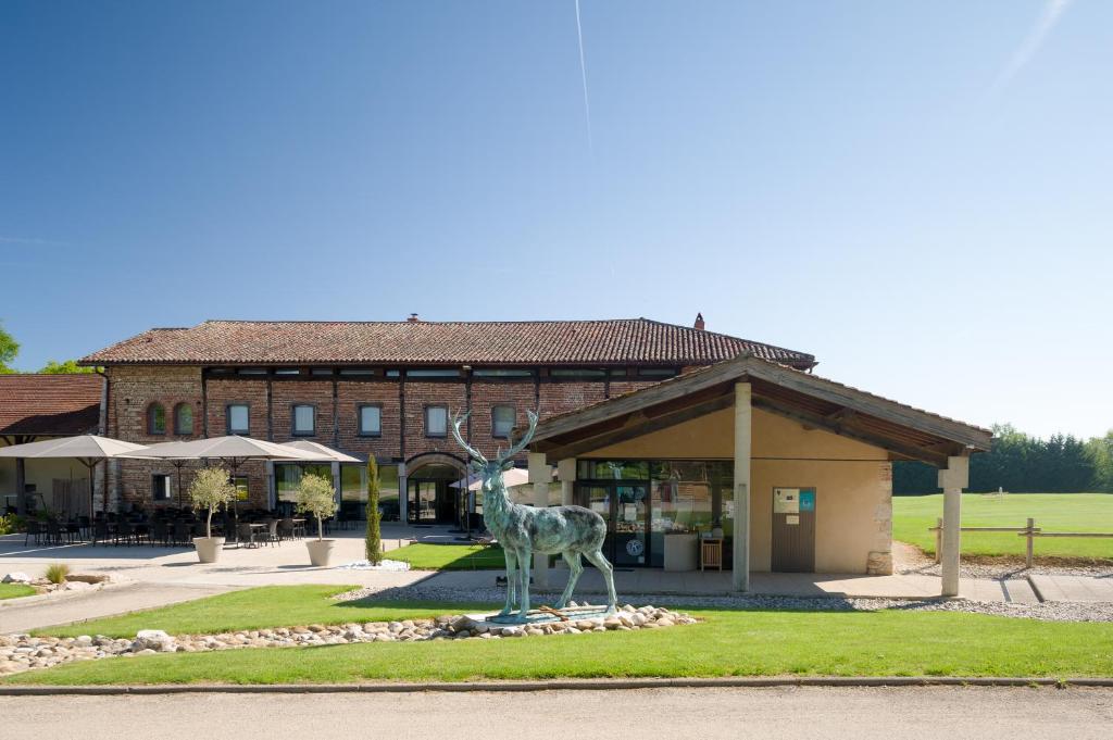 una estatua de una jirafa delante de un edificio en La Sorelle Hôtel Golf et Restaurant en Villette-sur-ain